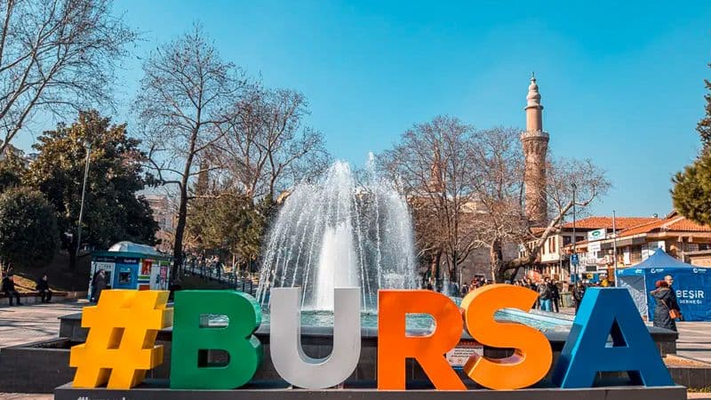 The colourful #BURSA sign and fountain in the old city, a minaret behind